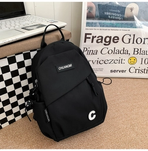 Detail of black nylon backpack featuring brand logo labels and side drawstring pockets