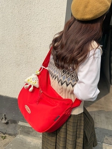 Large red nylon crescent crossbody bag with adjustable strap and plush cheese charm