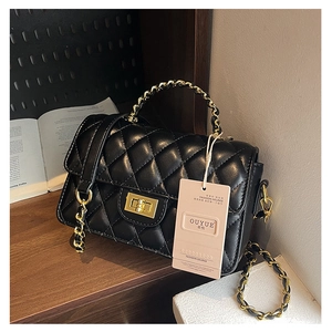 Detail view of a black quilted leather flap bag with a golden turn-lock closure and chain