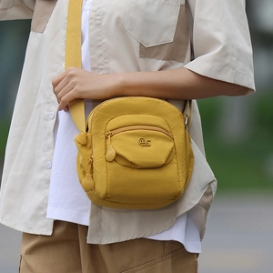 Détail d'un sac bandoulière en nylon jaune vif avec plusieurs poches zippées et sangle