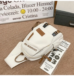 Close-up of white crossbody chest bag with brown leather accents and branded text detail