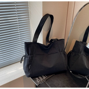 Detail view of large black canvas tote bag with drawstring feature and woven brand tag