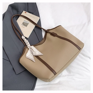Macro detail of khaki tote bag with lychee texture and silk scarf handle decor