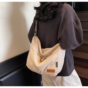 Détail du sac hobo en nylon beige avec logo en cuir marron et accents triangulaires