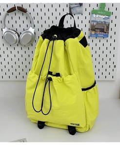 Detail of a bright yellow waterproof nylon drawstring backpack with multi-pocket design