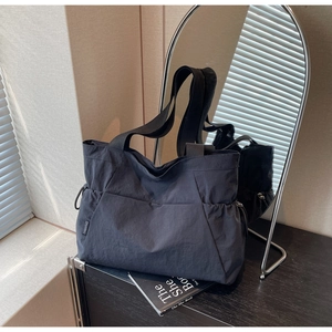 Detail of black nylon tote bag with drawstring closure and reinforced shoulder straps