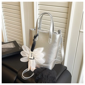 Detail der silbernen Mini-Tasche mit großer weißer Stoffblume und feinem Schultergurt