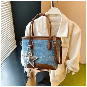 Détail du sac cabas en jean avec bordures en cuir marron et breloque étoile argentée