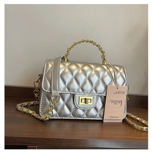 Detailed view of silver quilted crossbody bag with gold chain and rotary lock
