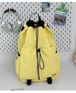 Close-up of yellow and black drawstring sports backpack with TUTIE embroidery on table