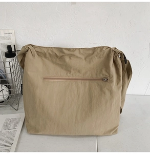 Detail of khaki nylon drawstring bucket bag with metal zipper pocket in minimalist setting