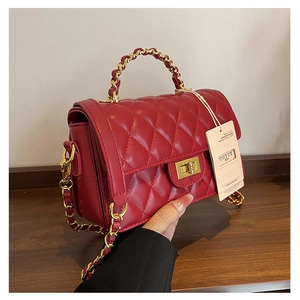 Detail view of red quilted leather crossbody bag with gold handle and chain strap
