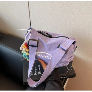 Close-up of purple nylon dumpling bag with white lettering and cartoon doll charm