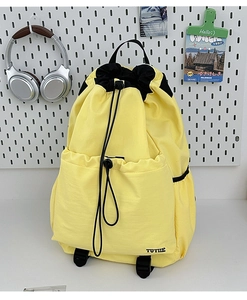 Detail of yellow drawstring backpack showing waterproof nylon fabric and front pocket