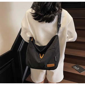 Vue arrière d'un grand sac bandoulière en toile noire avec large sangle réglable