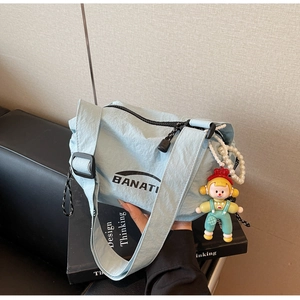 Close-up of light blue nylon bag with a cartoon doll pendant and white pearl chain detail