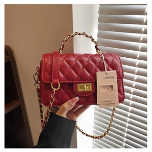 Detail of red quilted leather handbag with gold chain strap and top handle