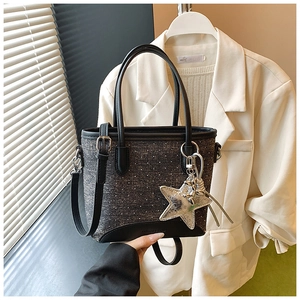 Détail du sac cabas en denim noir avec breloque étoile et anses en cuir