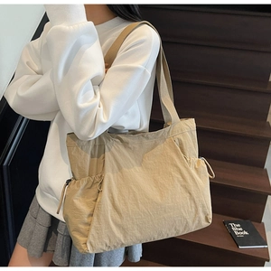Detail of khaki nylon tote bag featuring side drawstrings and light wrinkled texture material