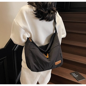 Détail du grand sac bandoulière en toile noire avec étiquette en cuir CHUANGMI