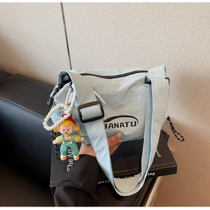 Detail of light blue nylon shoulder bag with BANATU logo and pearl doll charm