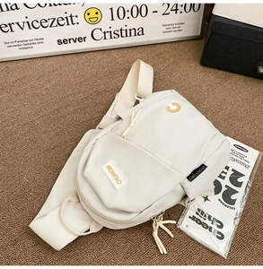 Close-up of off-white nylon chest bag featuring multiple zipper pockets and brand labels
