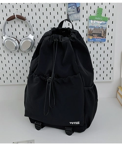 Detail of a black drawstring backpack with front pocket and adjustable buckles on nylon straps