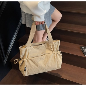 Close-up of beige nylon tote bag with drawstring detail on a wooden staircase