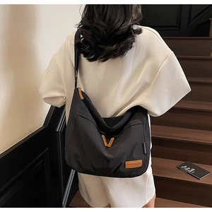 Détail d'un grand sac fourre-tout noir en toile avec logo en cuir porté à l'épaule