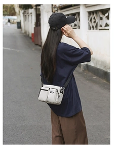 Outdoor crossbody bag in off-white canvas shown on model for a street leisure look