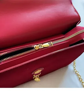 Detailed close-up of the smooth gold-tone zipper on a classic red leather evening handbag
