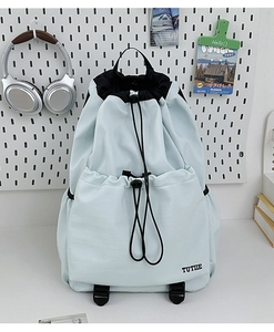 Detail of light blue drawstring backpack with TUTIE logo and durable nylon texture