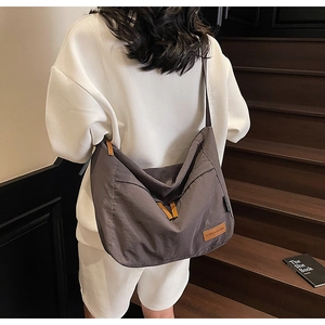 Gros plan d'un grand sac bandoulière en nylon gris foncé avec logo en cuir et bandoulière large