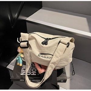 Detail of beige nylon shoulder bag with BANAT logo and cute cartoon boy charm