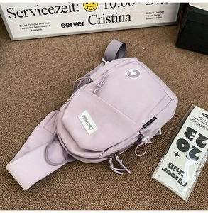 Detail of lavender nylon crossbody bag with zipper compartments and brand logo on texture