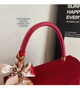 Detail of red velvet handbag with a rigid round handle and floral printed silk scarf