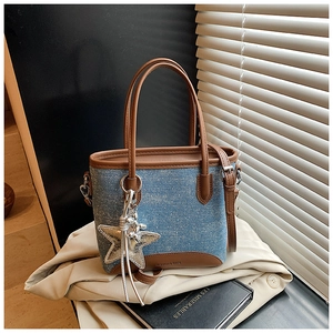 Détail du sac seau en denim à pois bleus avec garniture en cuir marron et breloque étoile