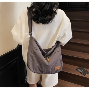 Détail d'un sac bandoulière en toile avec poche latérale porté sur un sweat blanc