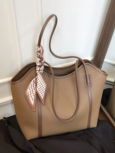 Caramel brown leather tote bag with elegant silk scarf on a clean studio background