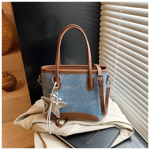 Détail du sac seau en denim et cuir avec breloque étoile sur fond stylisé élégant