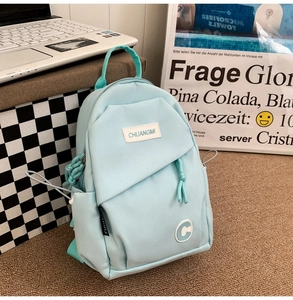 Detail of light blue nylon bag with brand patch in a casual campus-style setting