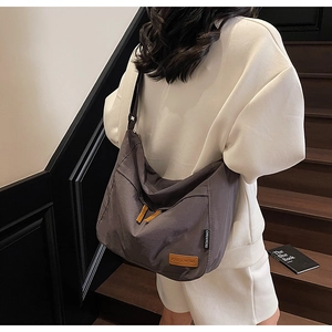 Détail du grand sac cabas gris foncé en toile avec étiquette cuir porté par un mannequin