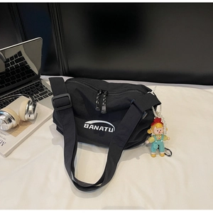 Close-up of black nylon crossbody bag with adjustable strap and decorative cartoon doll charm