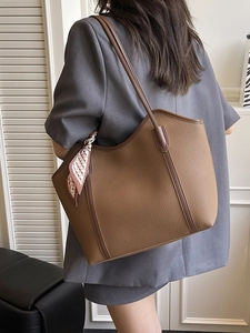 Brown leather tote bag with large capacity and silk scarf detail for elegant commuting