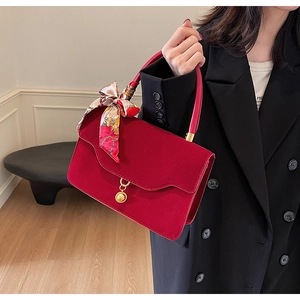 Detail of burgundy velvet bridal handbag featuring golden hardware and floral silk scarf wrap