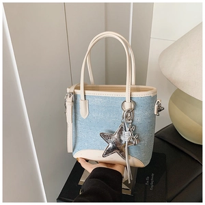 Détail du sac seau en jean avec pendentif étoile, perles et garniture en cuir blanc