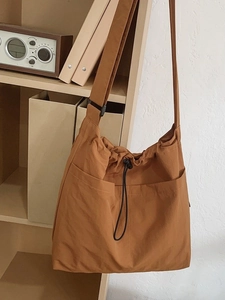 Large tan nylon drawstring bucket bag with adjustable shoulder strap for summer travel