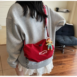 Detail of red nylon shoulder bag with BANATU logo and a cute doll pendant attachment