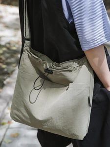 Olive green nylon crossbody bucket bag with drawstring pocket and adjustable strap