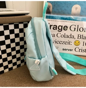 Detail of light blue nylon mini backpack with side pocket and mint green straps